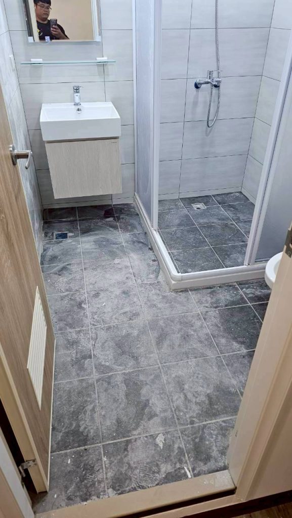 清潔前：浴室地板佈滿灰塵與施工殘留物，洗手台下方未整理。